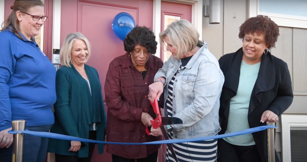 Executive Director Alison Kear cutting the ribbon with Mildred Mack accompanied by Amy Miller, Carol Gore, and Carlette Mack.