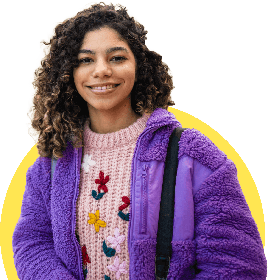 A young woman wearing a purple coat, smiling at the camera.