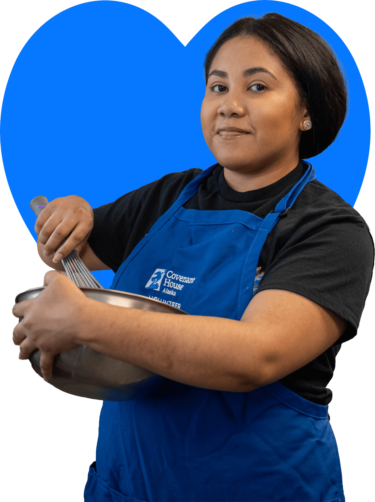A woman working with a mixing bowl wearing an apron with the Covenant House Alaska logo